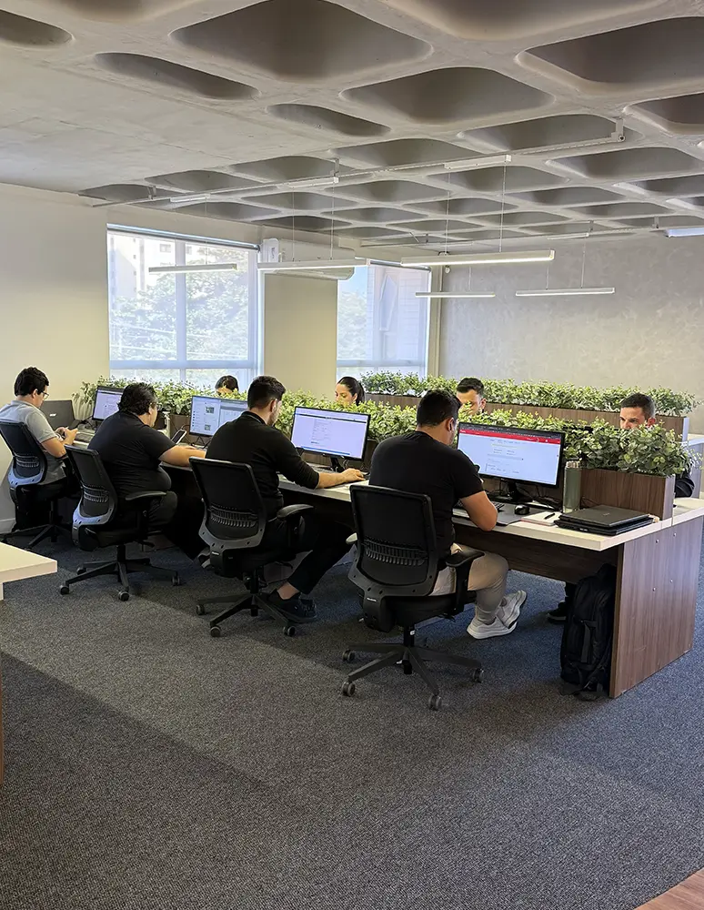 Equipe em escritório trabalhando em computadores, atendimento para seguros personalizados