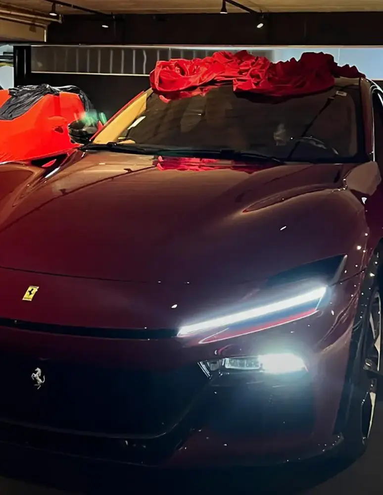 Carro esportivo vermelho com laço no capô em showroom, seguro auto personalizado para veículos de alto valor